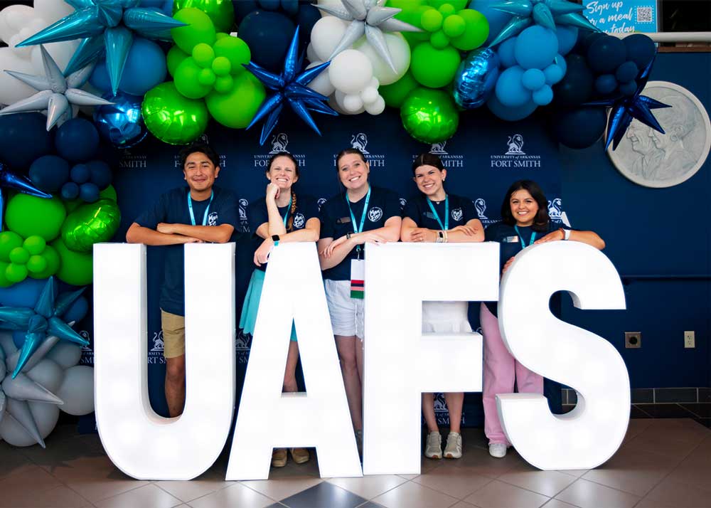 the UAFS admissions team poses with UAFS letters