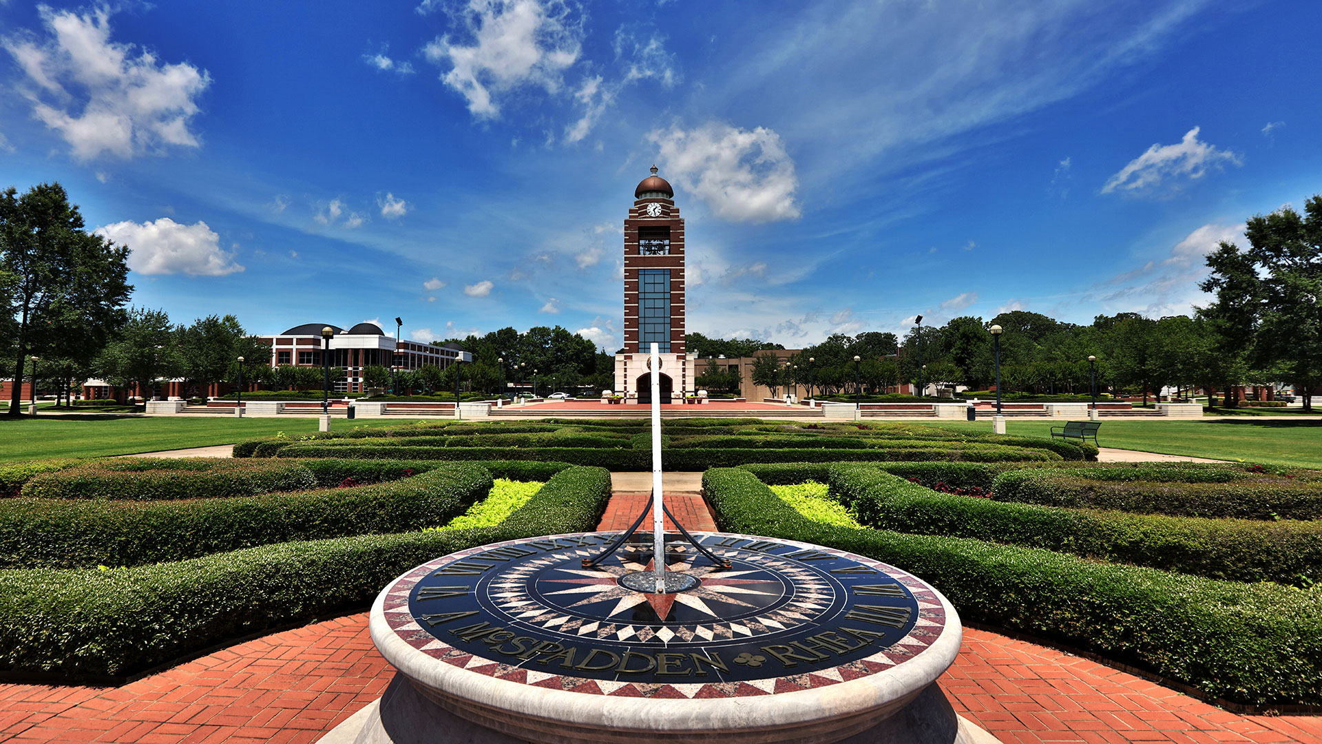 UAFS sundial stands in front of the university bell tower on a summer day
