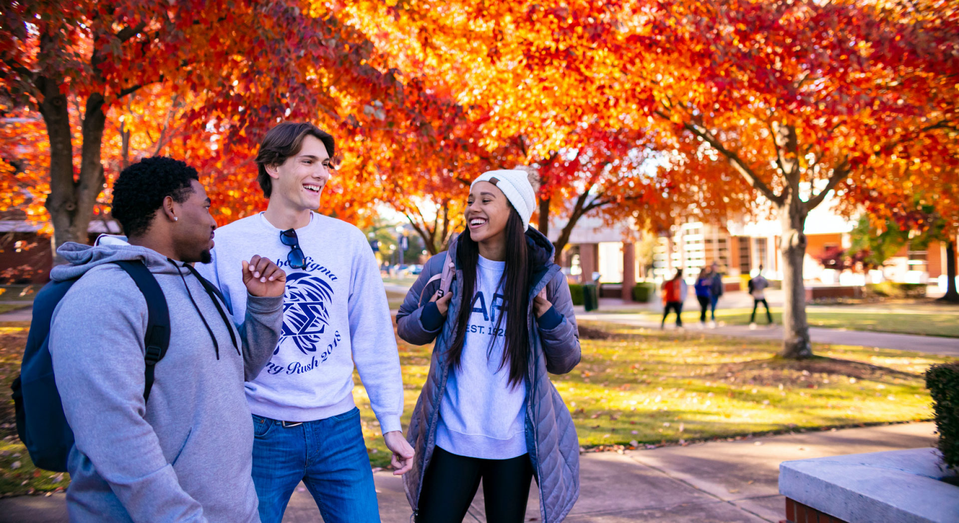 Student gather under red fall leaves