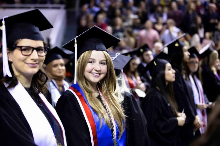 Graduates smile in their caps and gowns