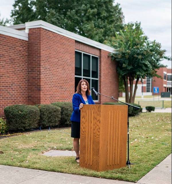 Chancellor Riley stands at a podium, looking at the camera, giving opening remarks about the Grand Opening of the Writing Center