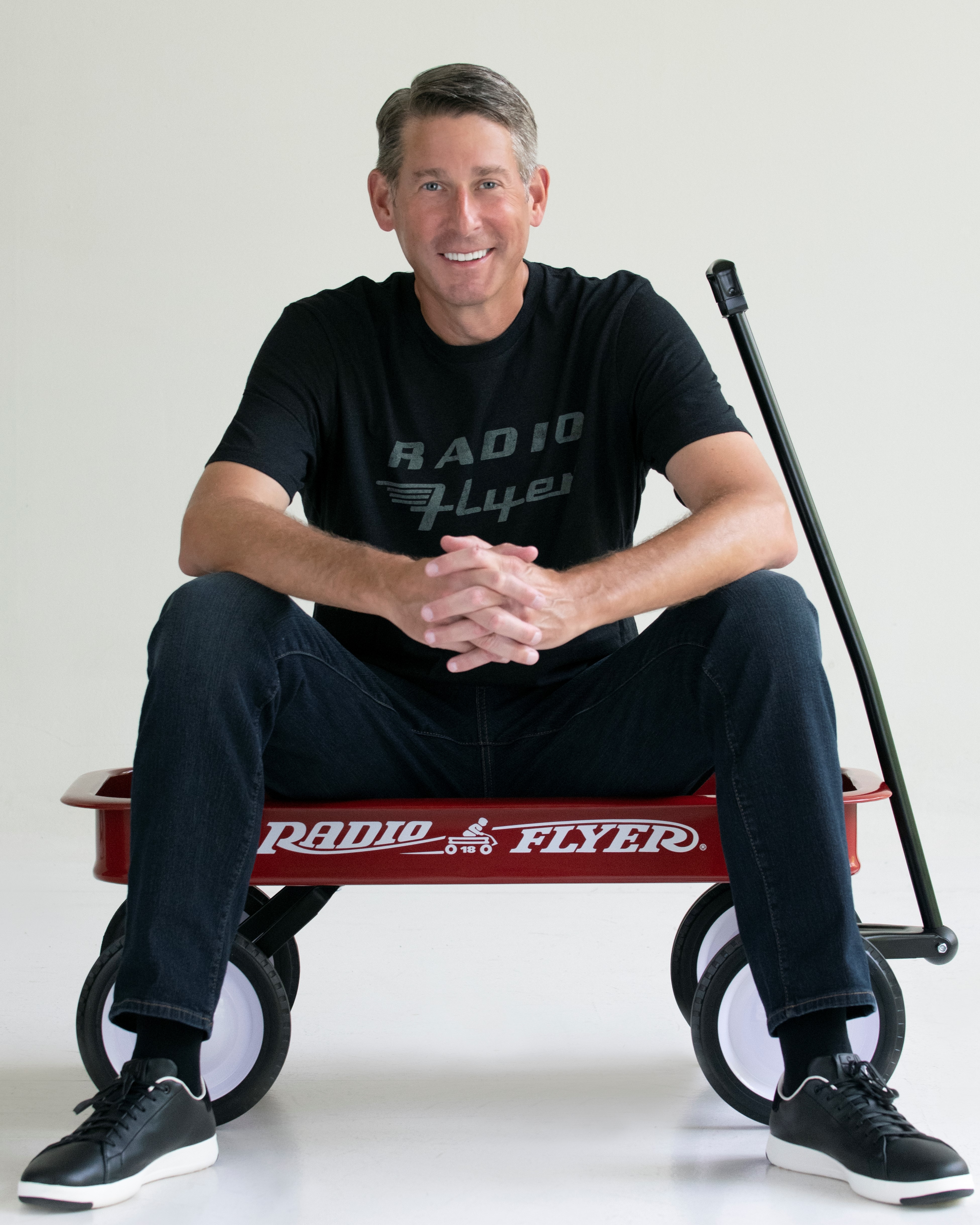 Robert Pasin sitting in a little red wagon