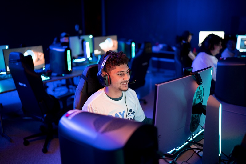A student plays an esports game in a dimly-lit gaming center