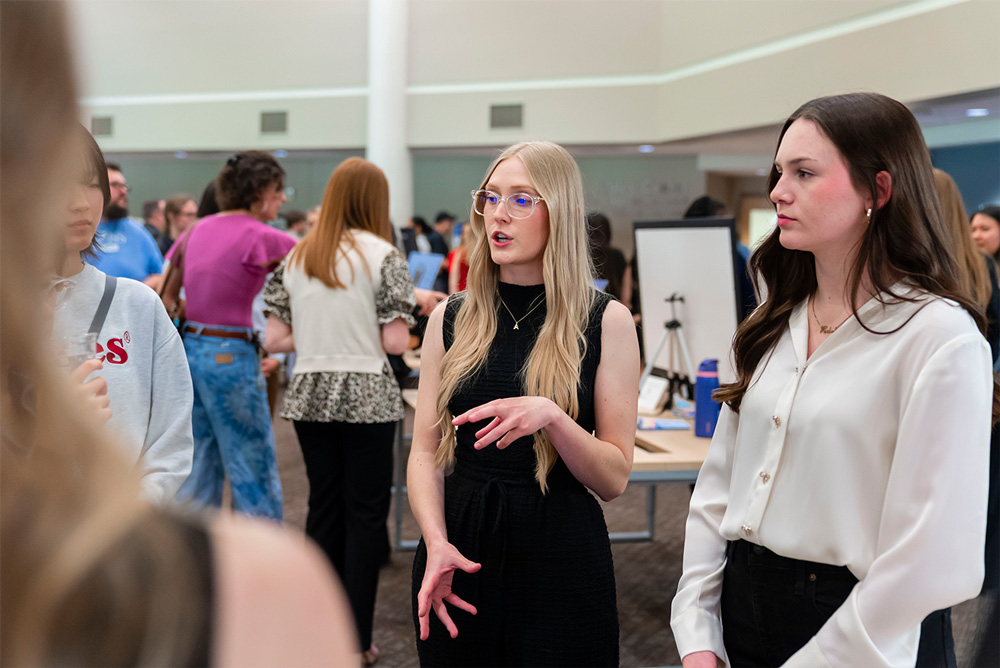 Two students talk about their research project at the 19th Annual Student Research Symposium