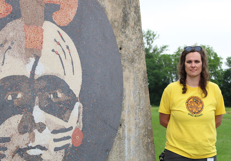 UAFS graduate Anna Vincent stands next to the entrance sign at the Spiro Mounds Archaeological Center