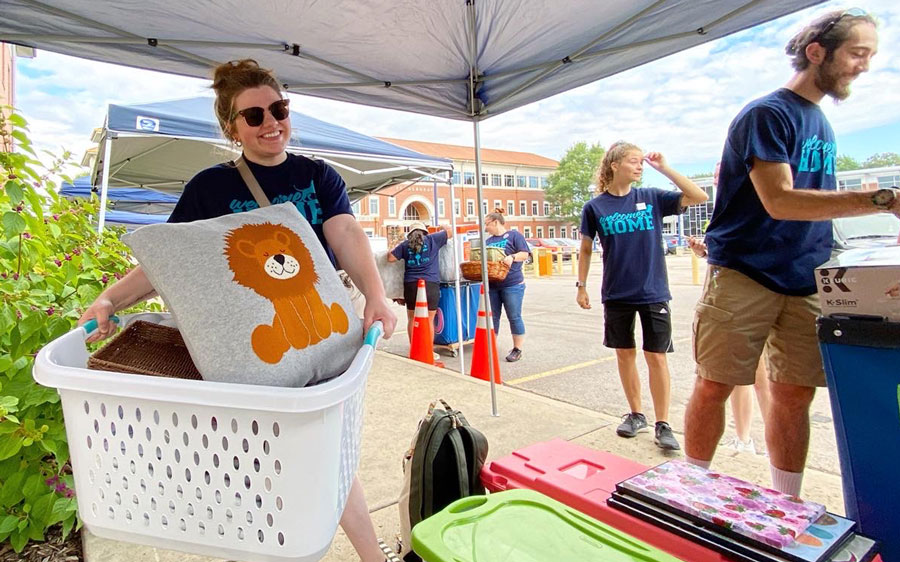 A NUMA Move-In Crew volunteer picks up a basket topped with a lion pillow