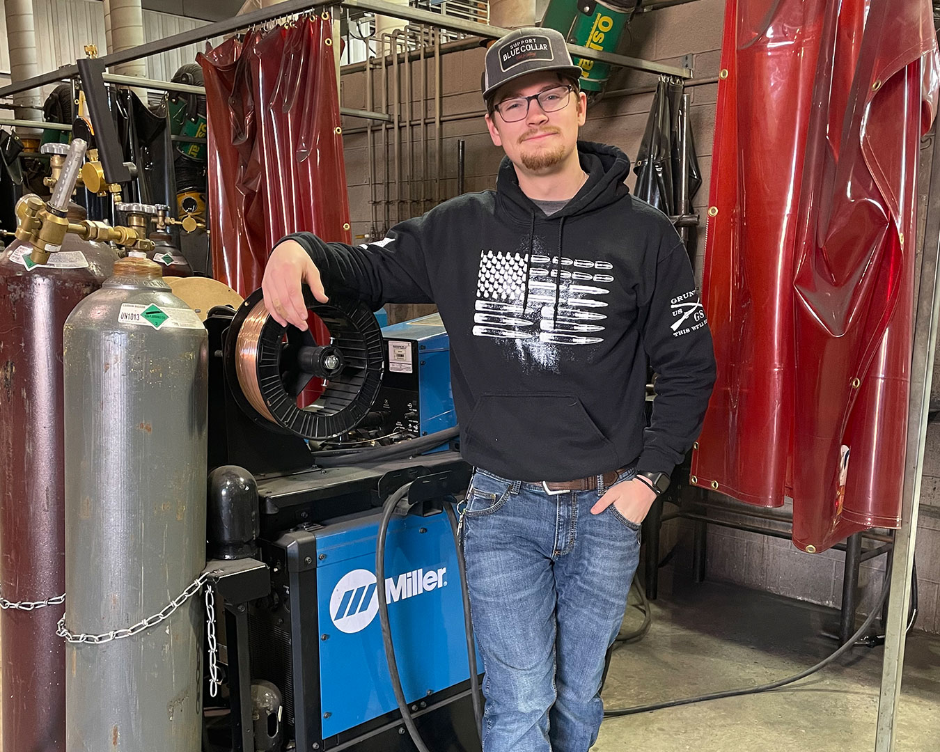 Student poses in front of welding station