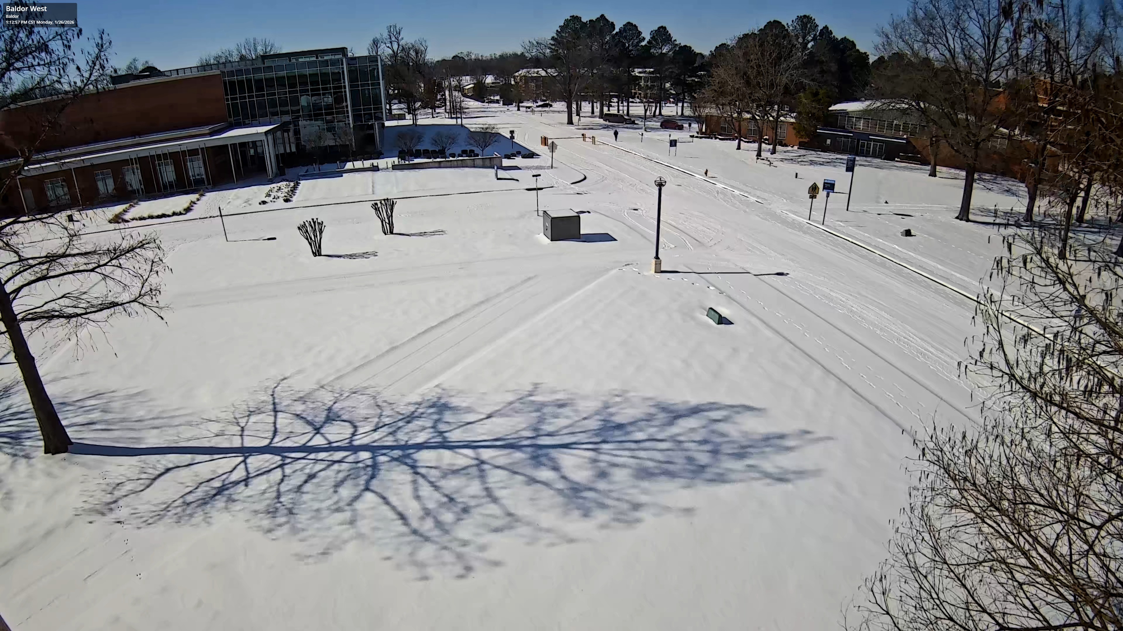 Snow-covered roadway and sidewalks on the UAFS campus with minimal vehicle activity following a winter storm.