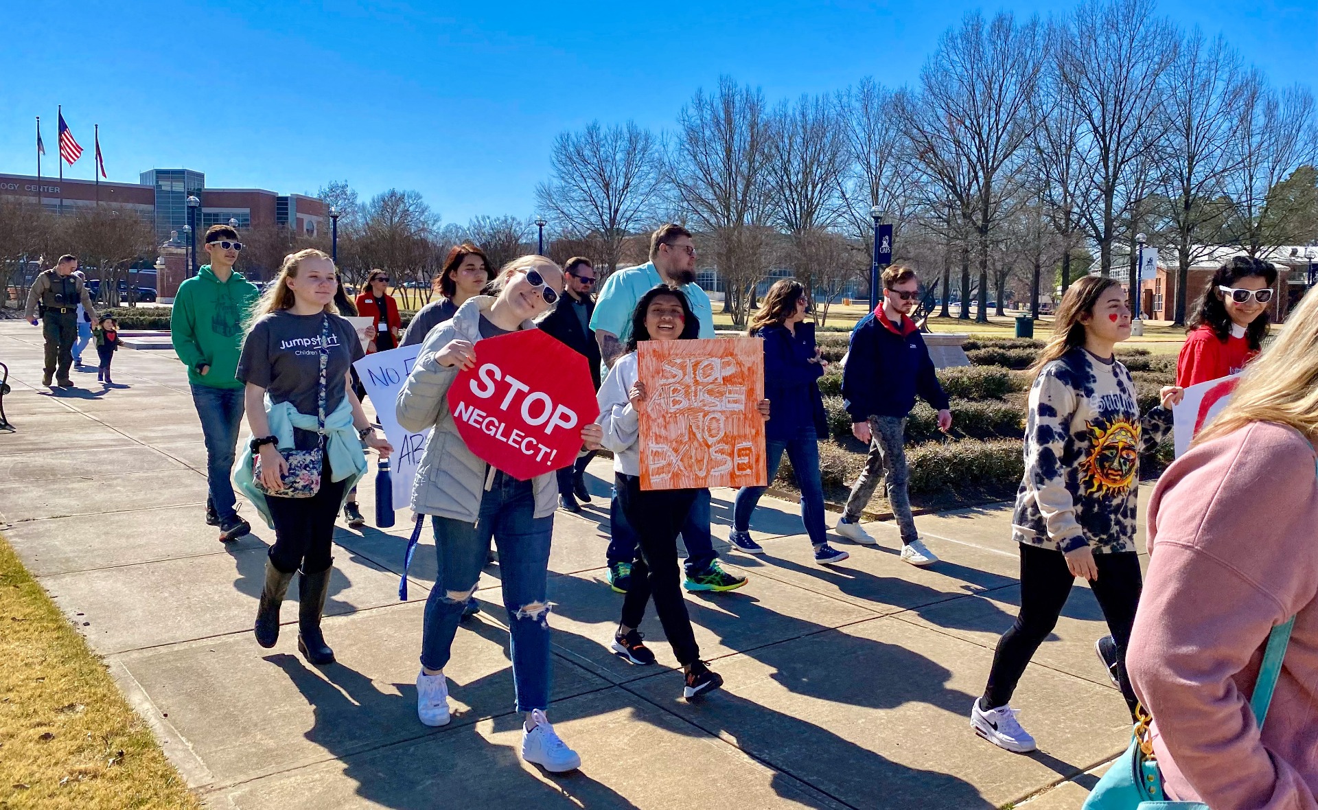students marching holding signs that state 