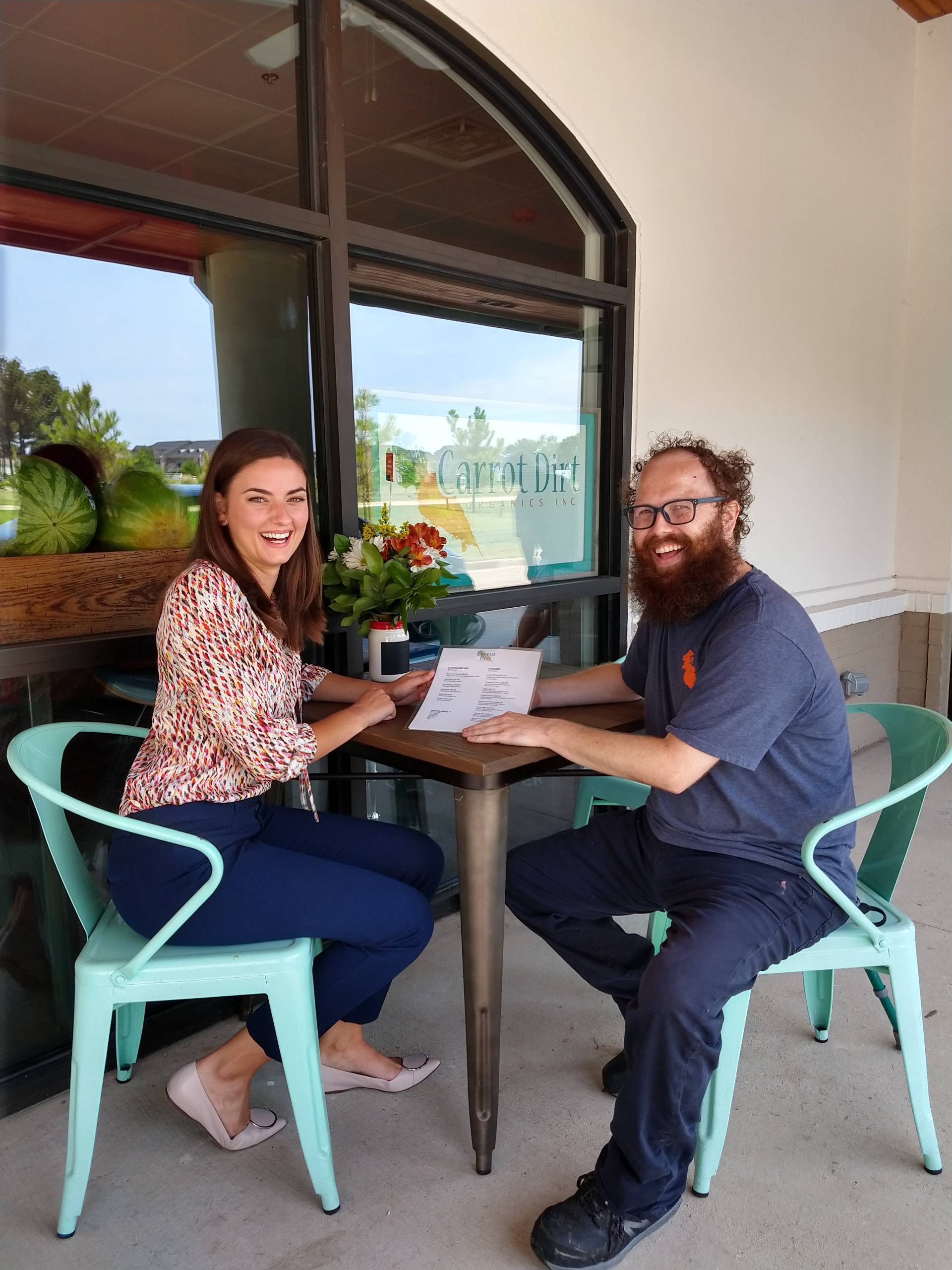Two people sit at a table outside.