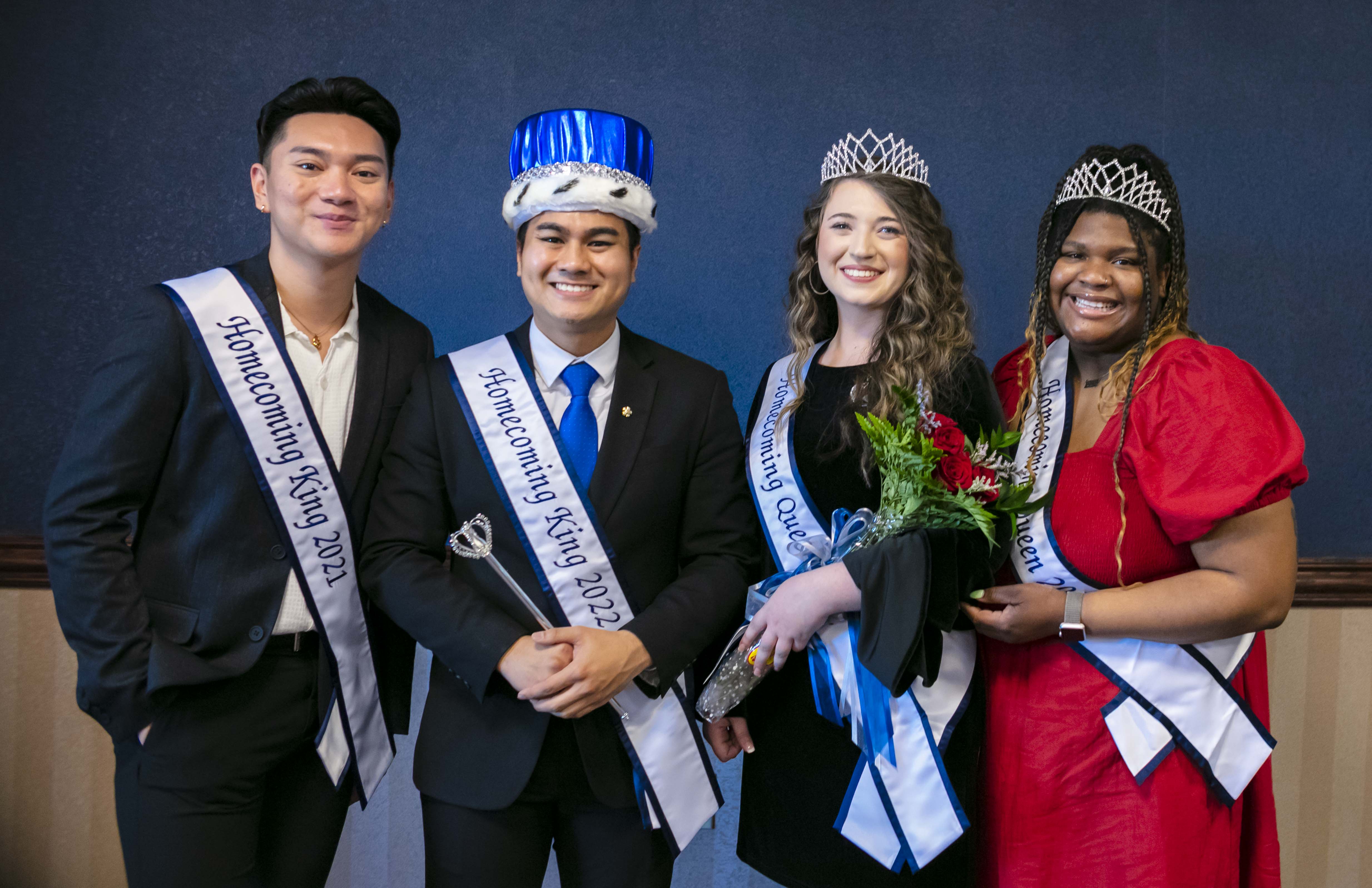 four students in a row with homecoming sashes, three with crowns.