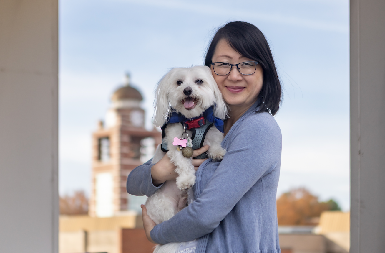 Dr. Ann-Gee Lee poses with her dog, Alfredo. The UAFS Belltower can be seen in the background.