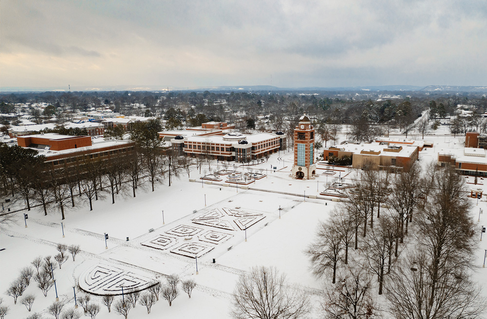 Aerial photo of a snow-covered UAFS Campus Green with the Bell Tower, Smith-Pendergraft Campus Center, Math Science Building, and Breedlove Building in the background.
