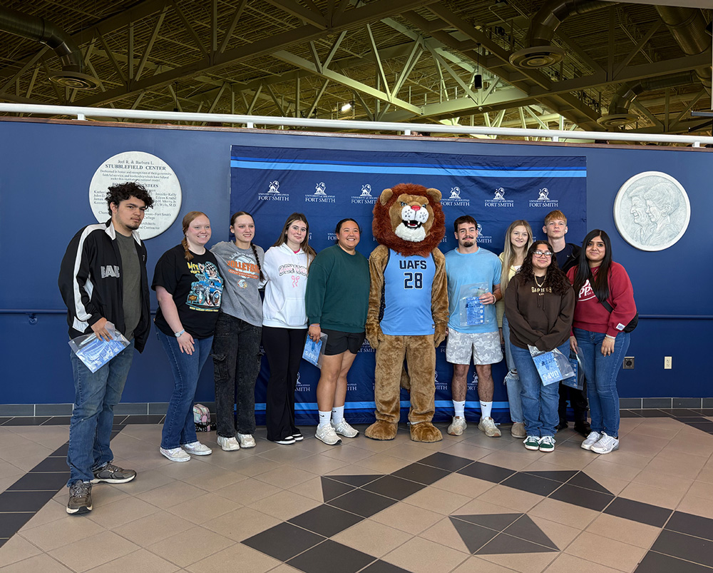 A group of 10 students pose with Numa at the Stubblefield Center during the UAFS fall Den Day