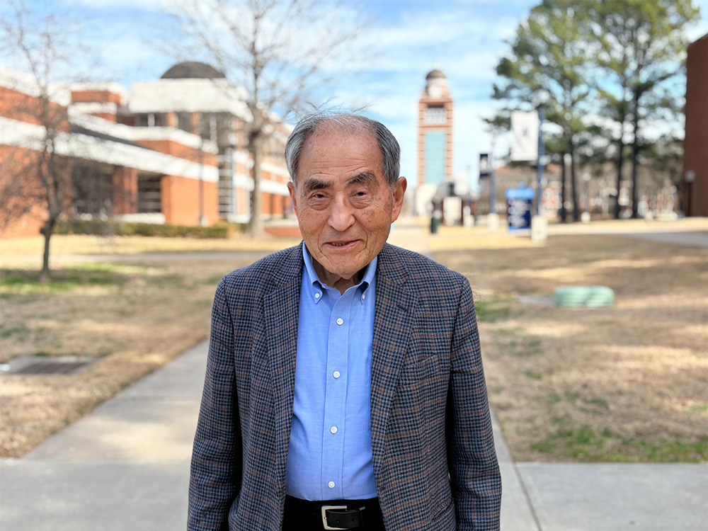 Dr. Bun Song Lee stands outside of the Smith-Pendergraft Campus Center with the UAFS Bell Tower in the background.