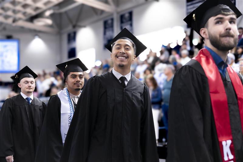 UAFS students smile as they walk through the stubblefield center at graduation