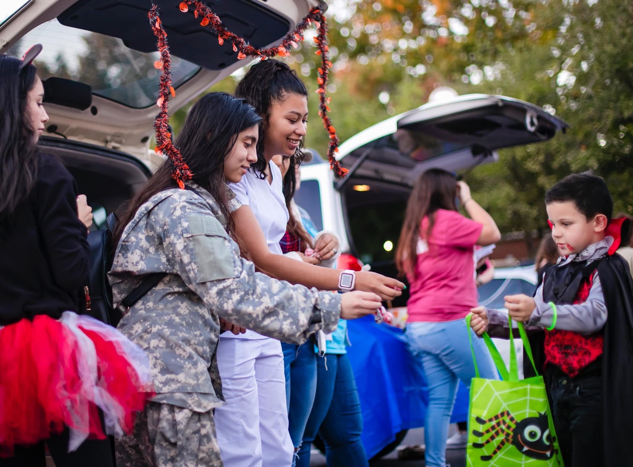 A child visits a trunk or treat stand with candy.