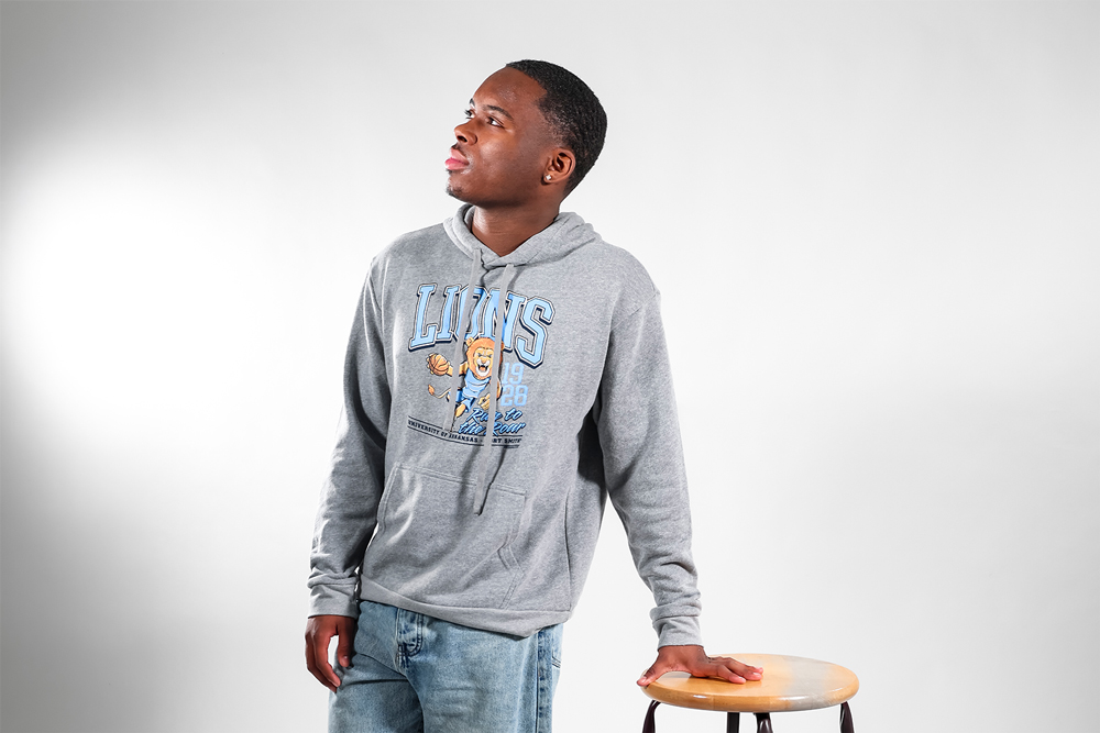 Jayden Robinson leans against a stool wearing a gray UAFS Lions Homecoming hoodie