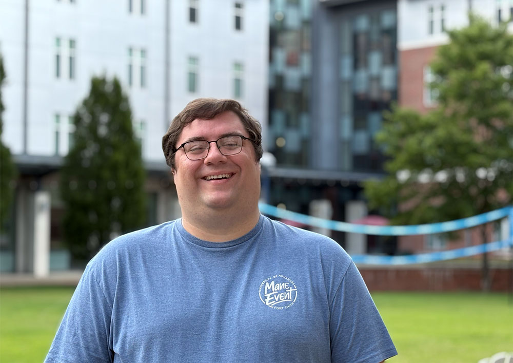 Joe England, resident director of the Lion's Den, smiles in the courtyard of the two dorms at UAFS