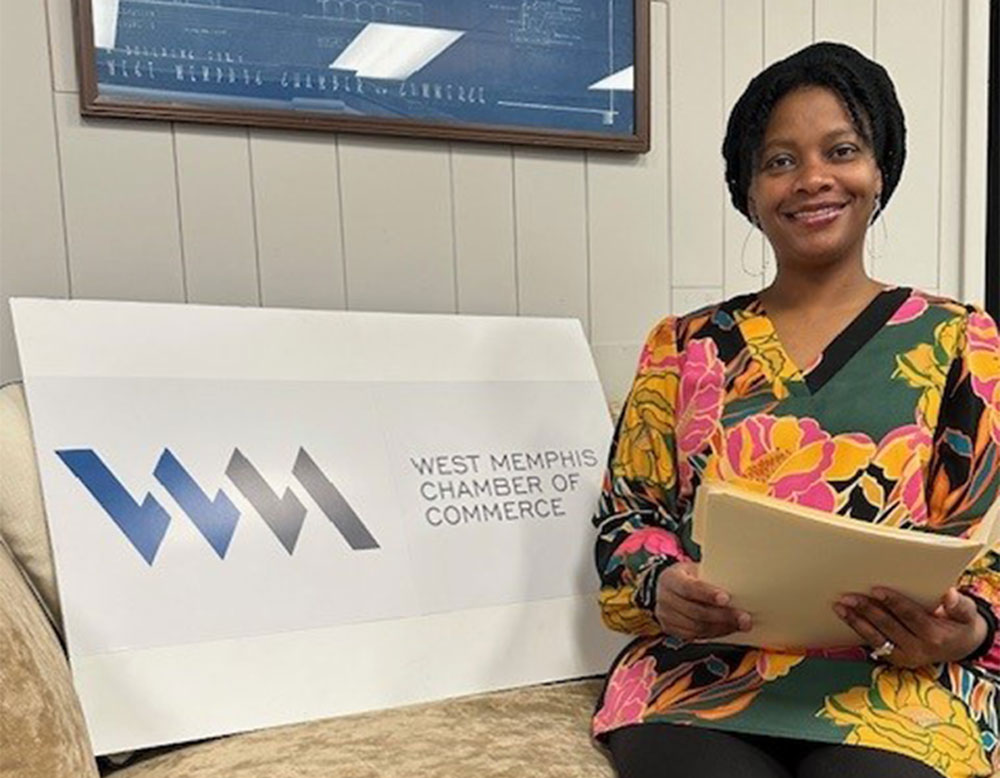 UAFS professor Dr. Kimberly Wolfe poses with West Memphis Chamber of Commerce signage after being elected to board of directors.