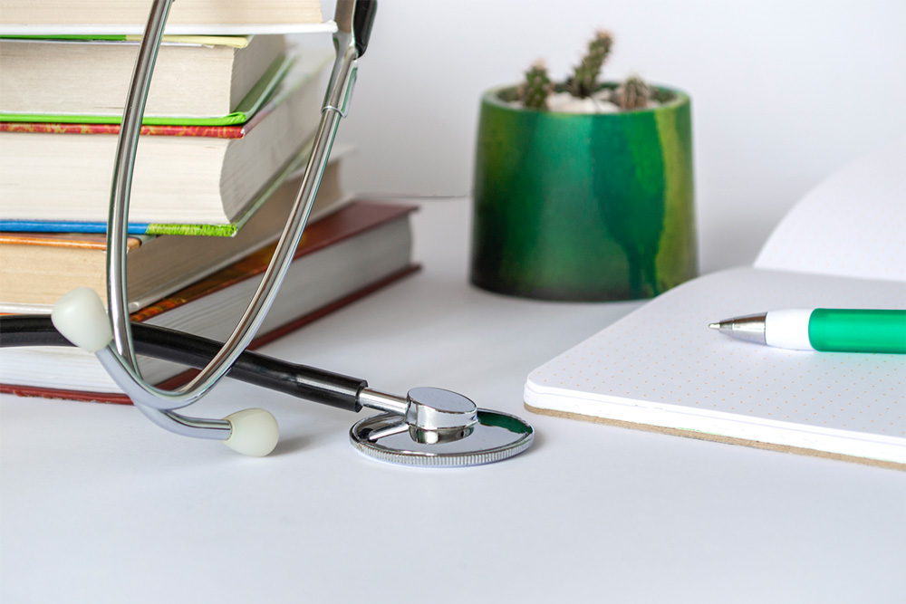 Doctor or student table with stethoscope, notepad, books.