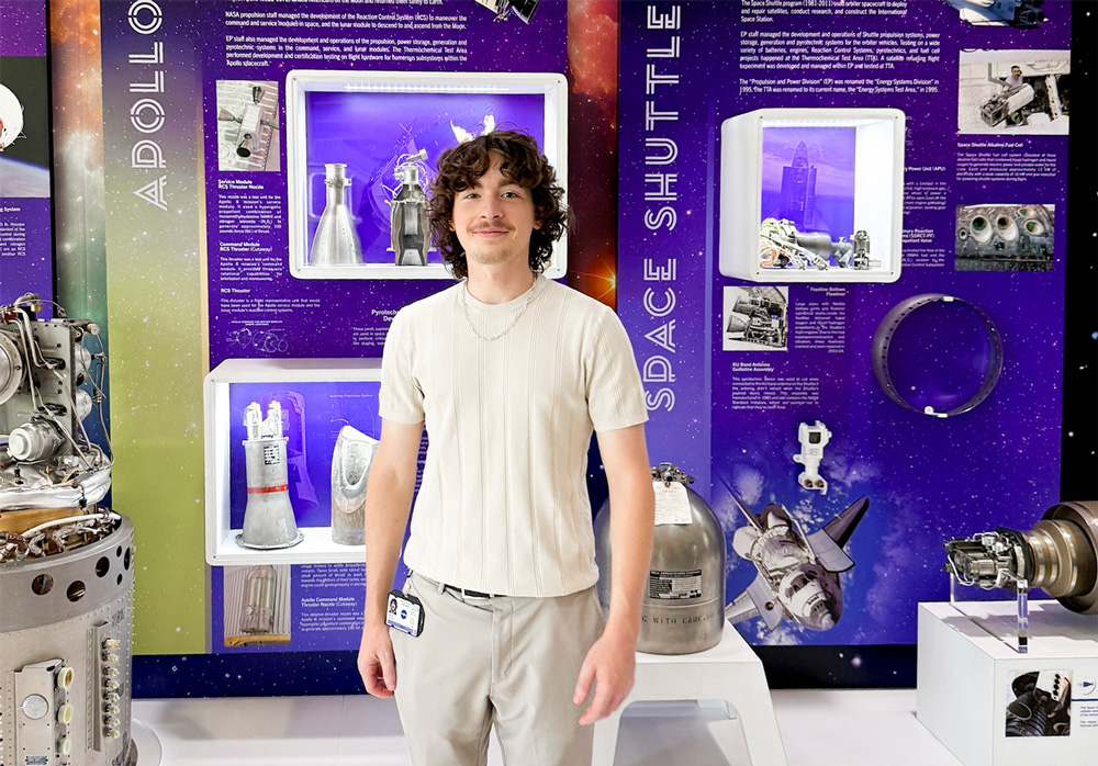 Hudson Reeves stands in front of a display at NASA's Johnson Space Center in Houston, Texas, during his summer internship.