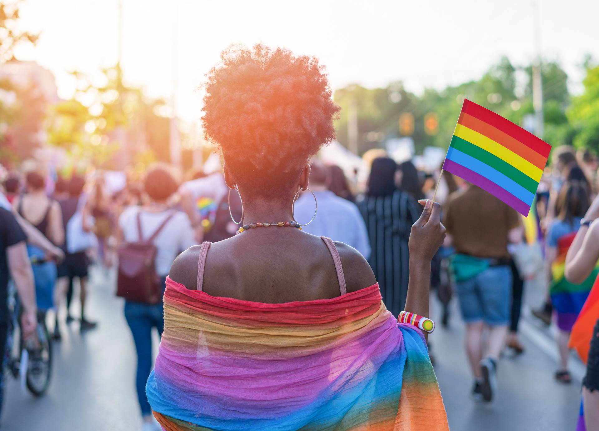 A woman in a rainbow shawl holds a rainbow flag