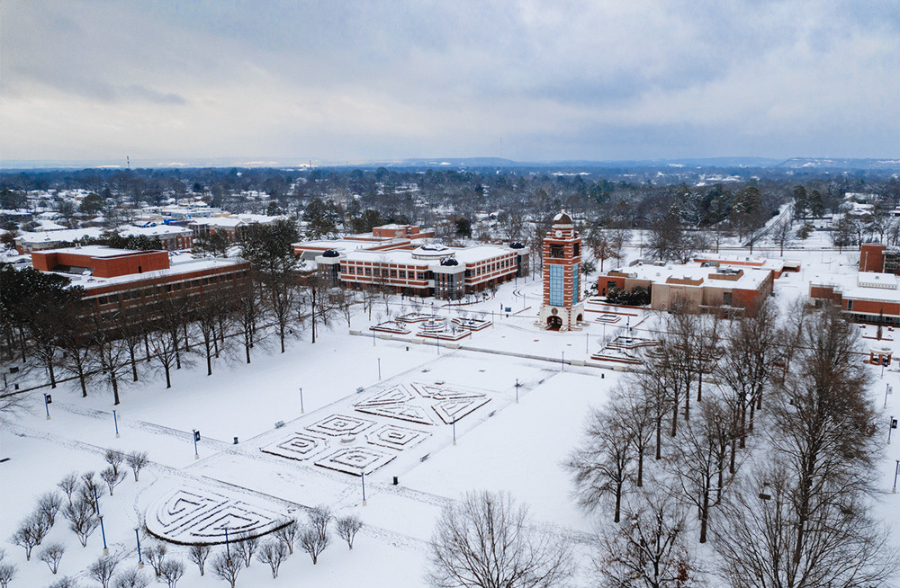 Aerial photo of a snow-covered UAFS Campus Green with the Bell Tower, Smith-Pendergraft Campus Center, Math Science Building, and Breedlove Building in the background.