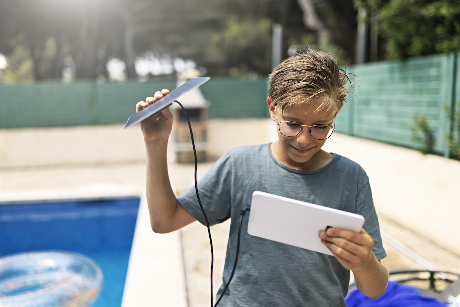 A teen uses a solar panel to charge his tablet