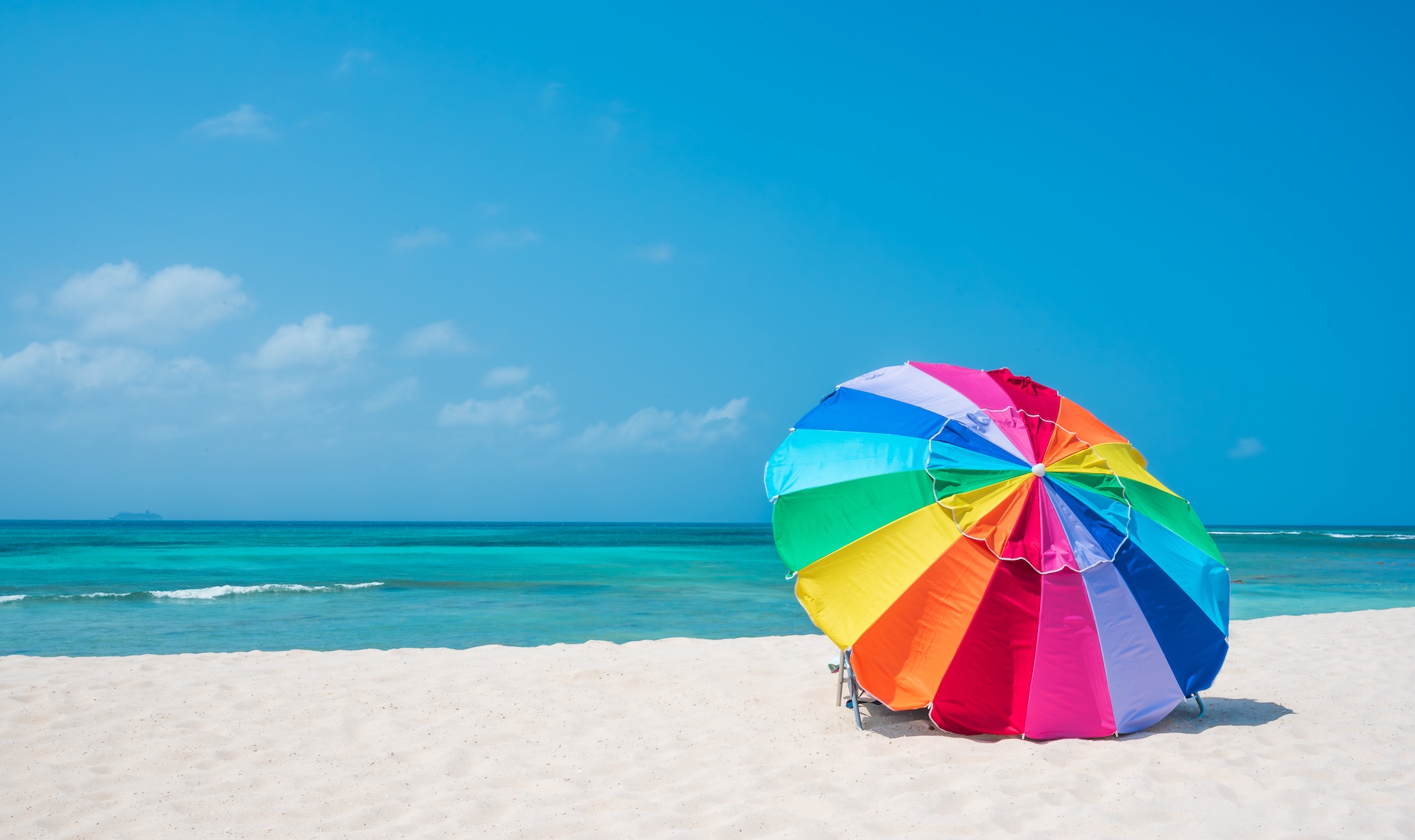 An umbrella casts shade on the beach