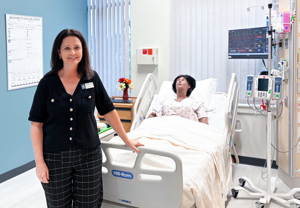 Dr. Tammy Rogers stands in front of a manikin in the Walter O. Caldwell Simulation Lab