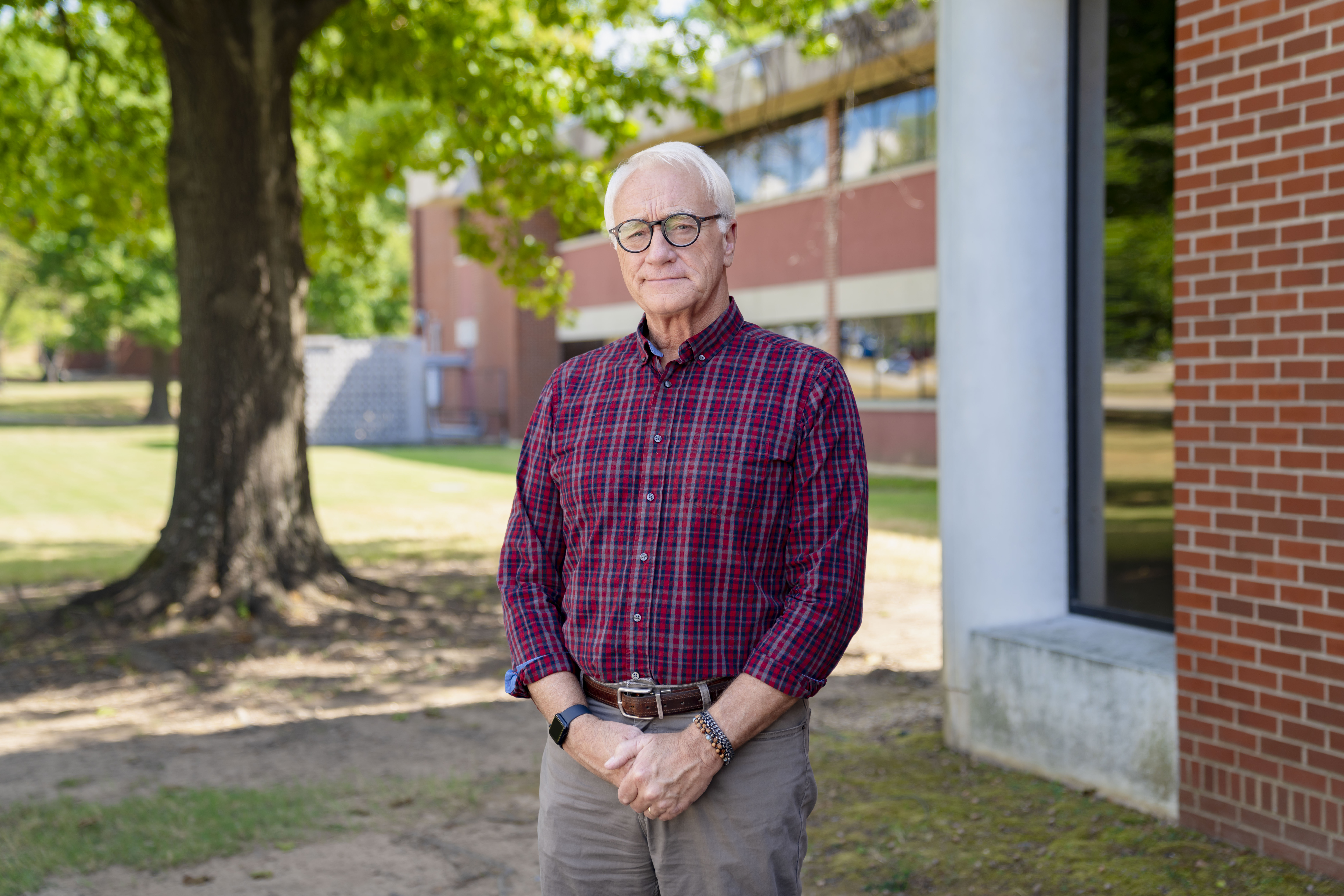 man standing outside in front of a building with tree in background