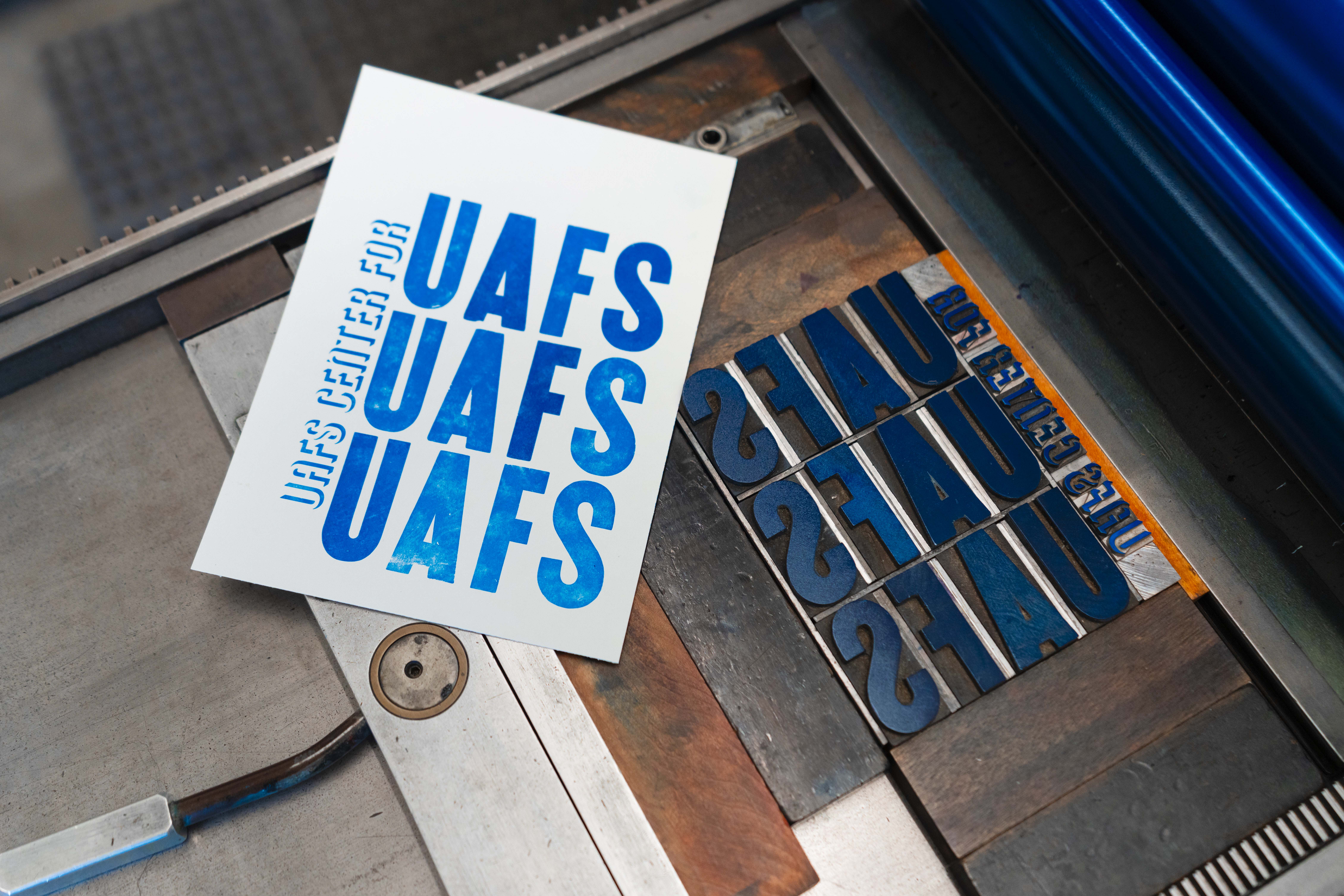 a printed card reads UAFS three times on an antique letter press
