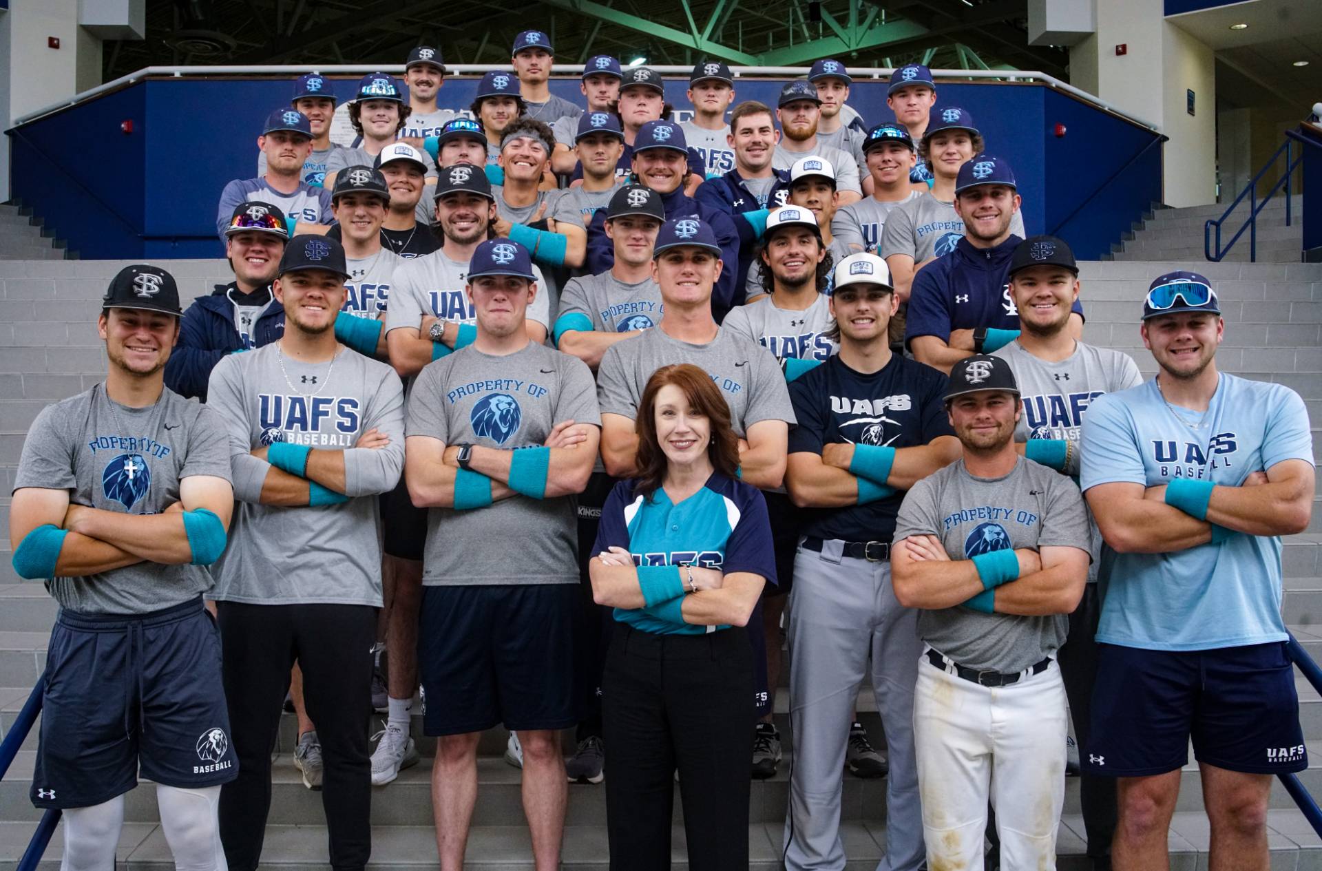 Chancellor Terisa Riley poses in a teal jersey honoring Sexual Assault Awareness Month with the UAFS Baseball team